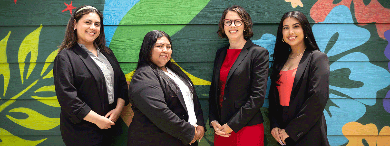 Adelante Legal team consisting of four lawyers standing in front of a colorful mural in Oakland, California.